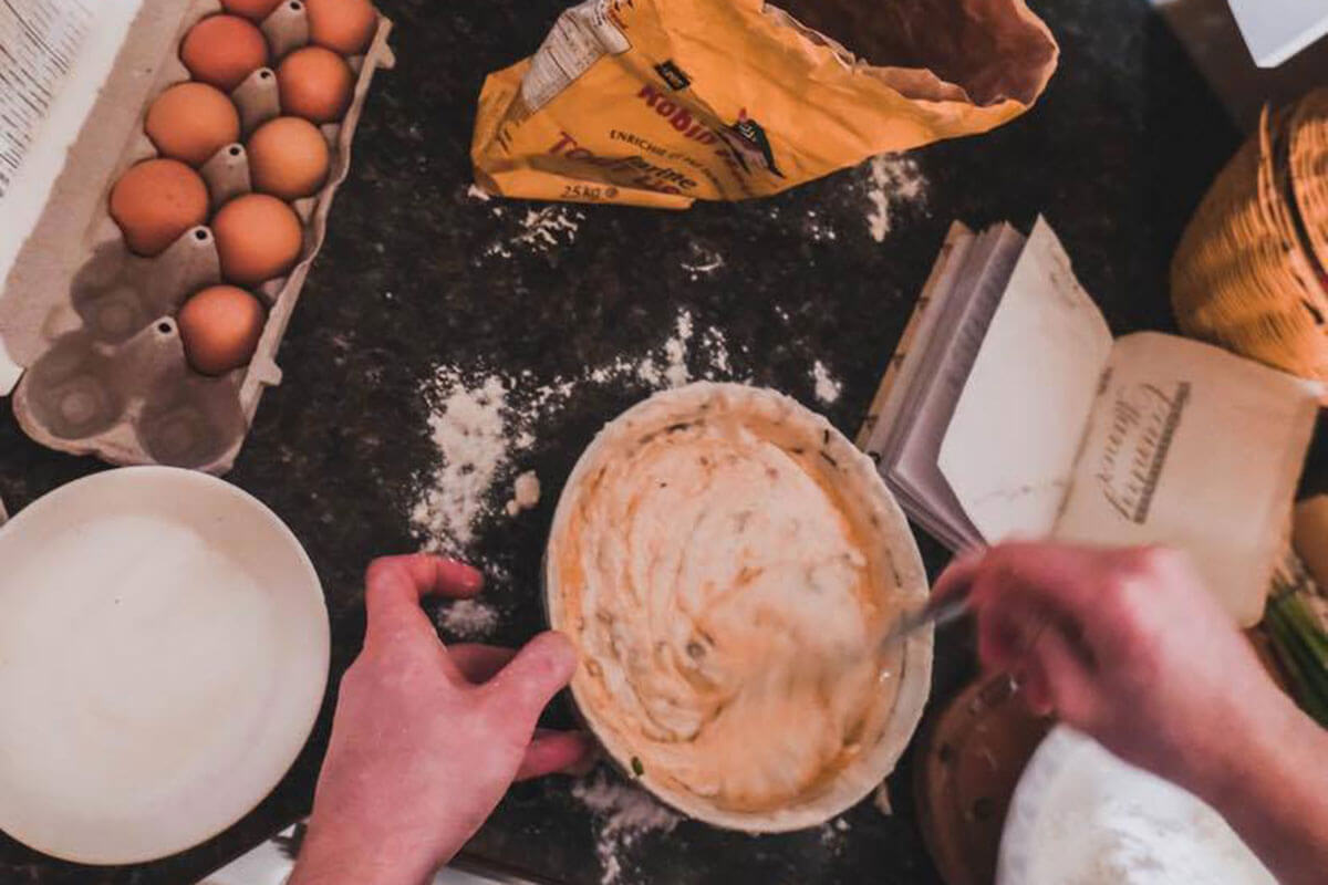 A mixture of baking ingredients and a person stirring a mixture in a bowl at SchoolHaus Culinary Arts