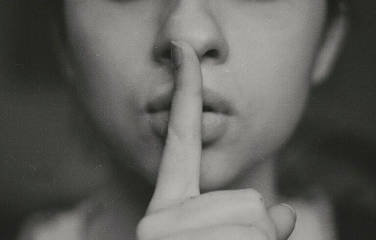 black and white image of a woman's face with her finger over her lips