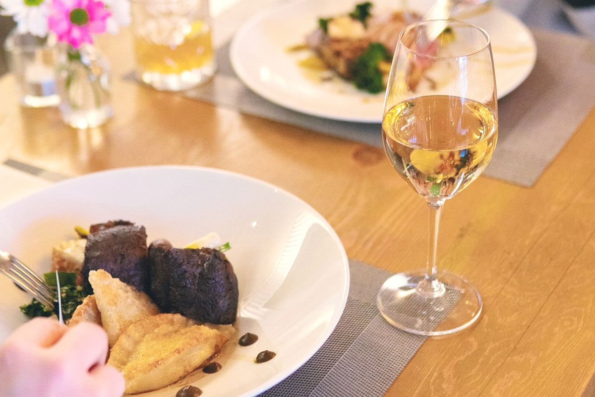 a plated course and glass of white wine in a 3 course dinner at Waterfront Restaurant & Wine Bar, part of food & wine in Kelowna