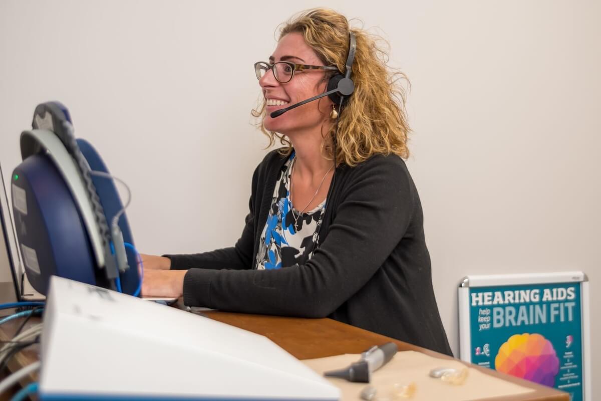 A hearing practitioner running a machine to test hearing loss