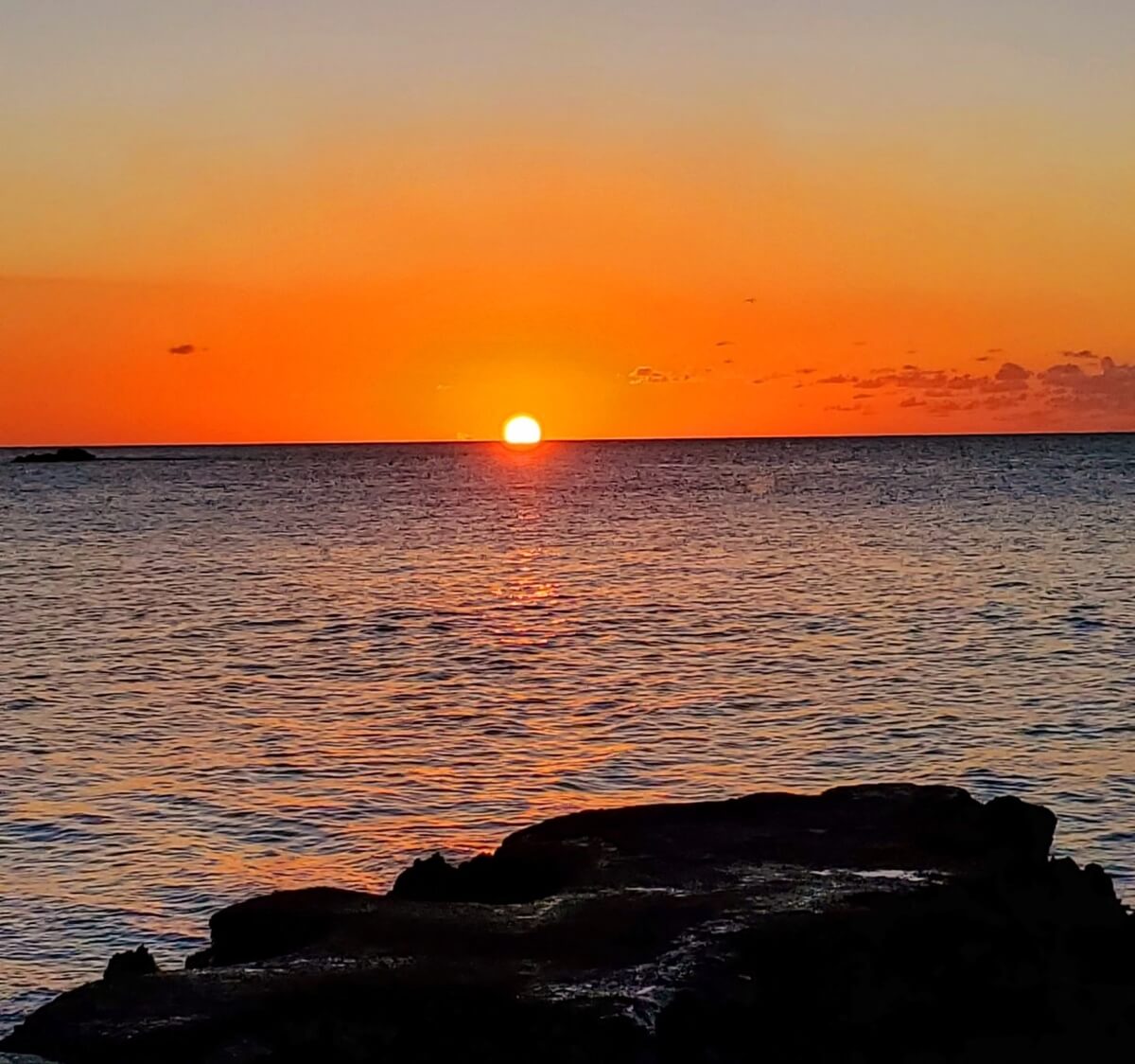 An orange Jamaican sunset over the ocean, part of Jamaica's one-love treasures