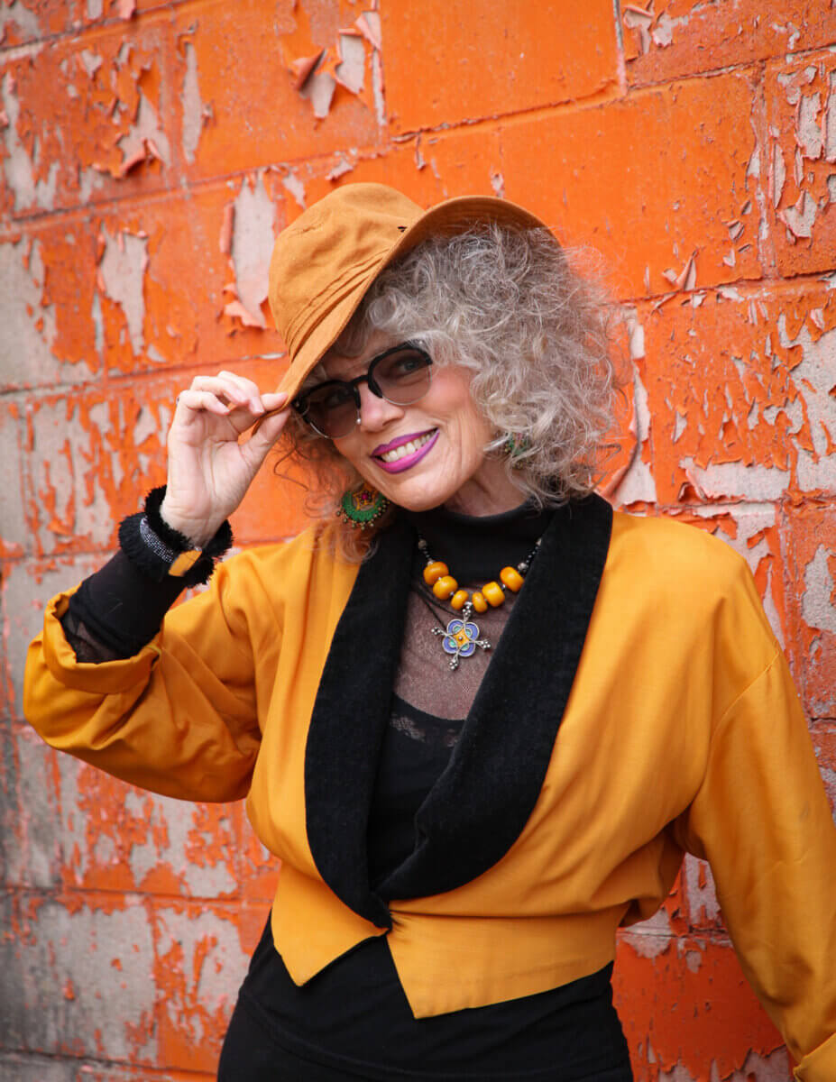 Mature woman living out loud, modelling an orange and black outfit and orange hat and sunglasses