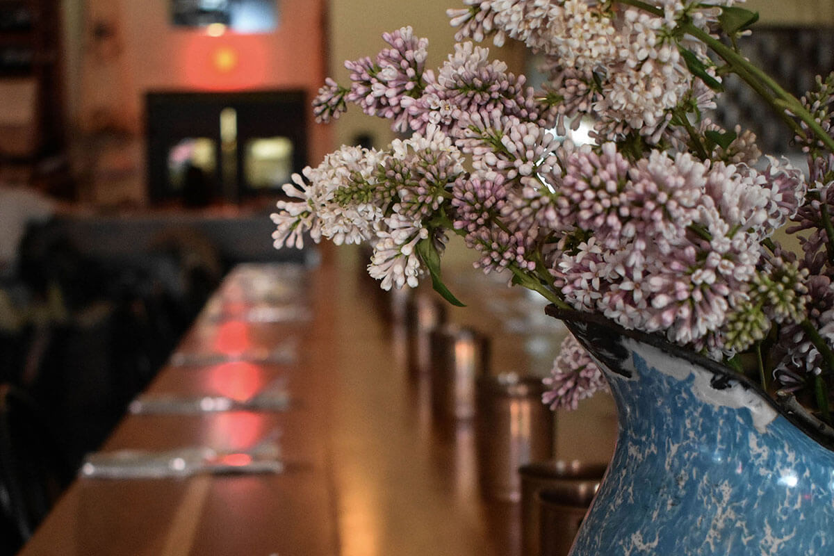 A blue vase of light purple flowers on a table set for dinner at Primal, part of the Saskatoon February City Guide