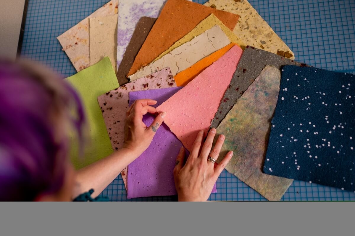A view from above of a woman looking at multi-coloured recycled paper samples for sustainable handmade gifts