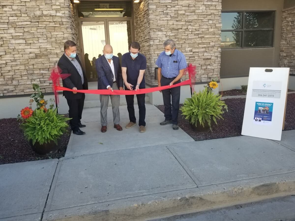 Four men hold and cut the ribbon at the official opening of The Caring Place