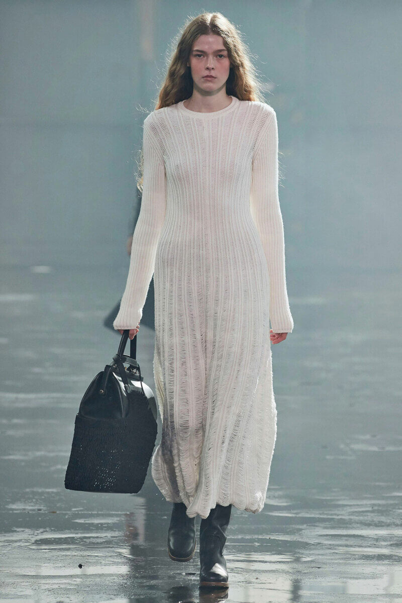 Model in long white knit dress , black combat boots and carrying black briefcase, by Gabriela Hearst RTW Fall 2021 fashion collections