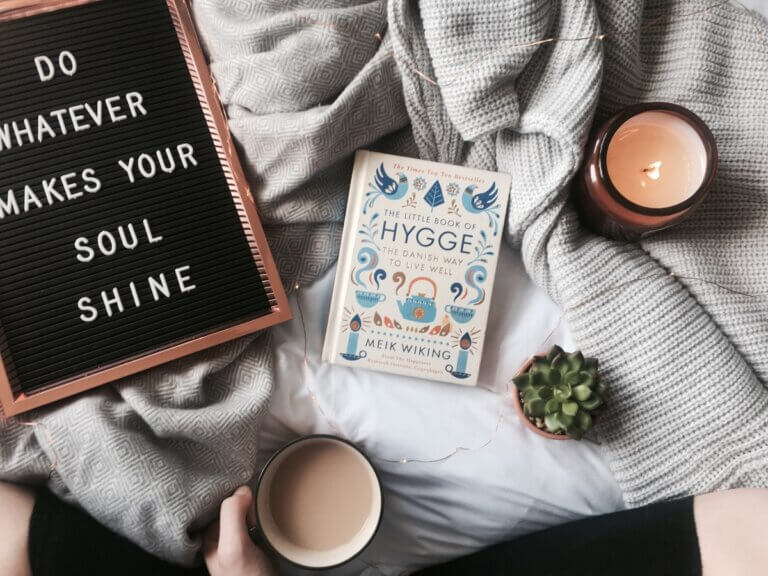 a sign, book, cup of coffee on a blanket, part of hygge healing