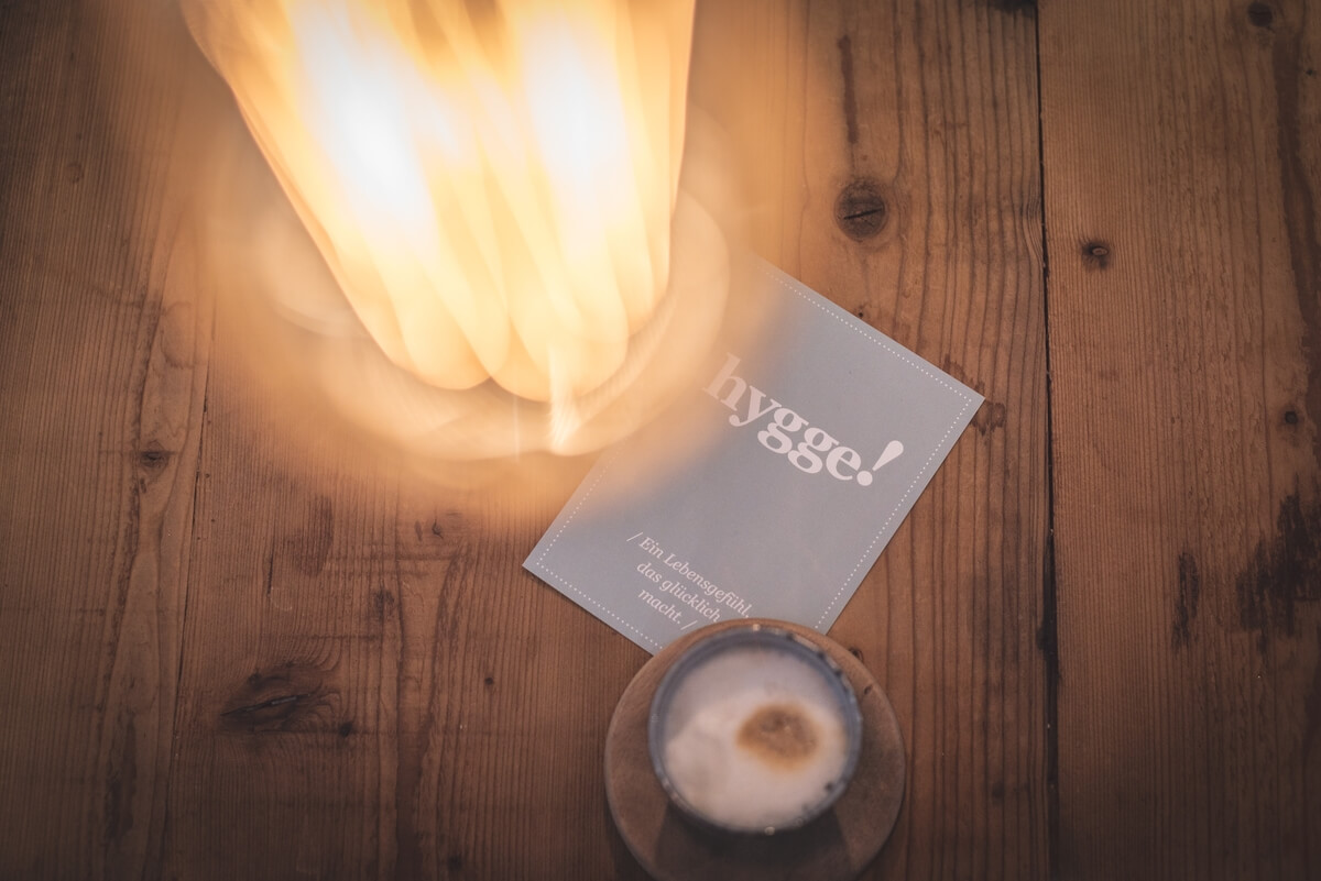 a candle, book and golden light on a wooden floor, essential for hygge healing