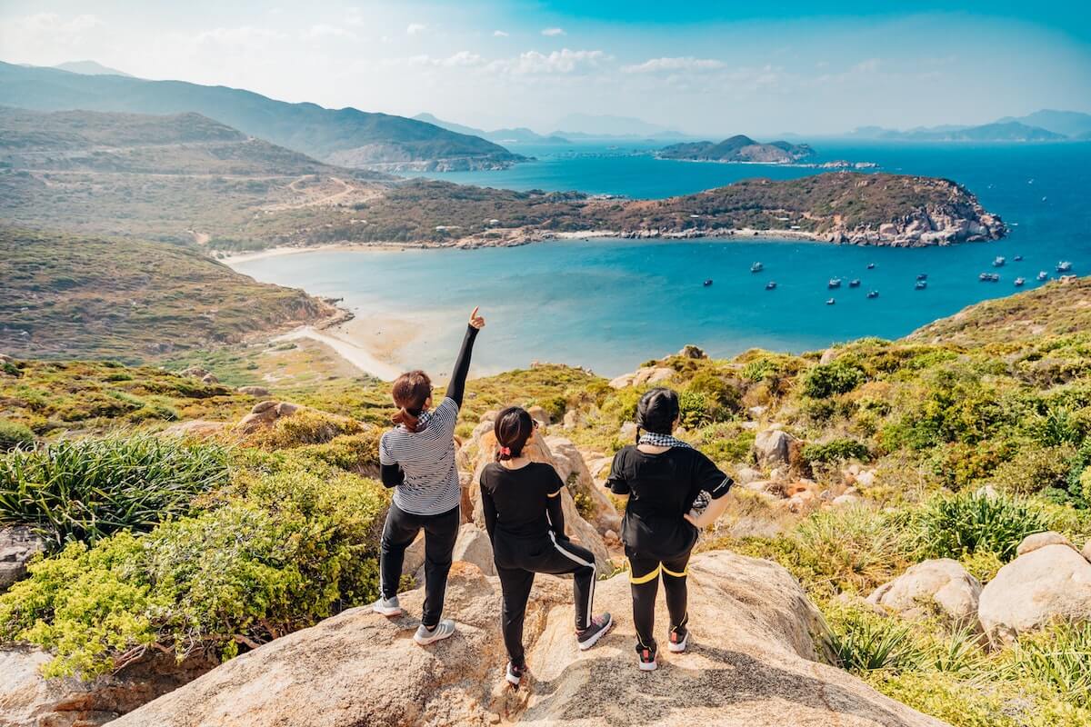 3 women overlooking a tropical coastal view