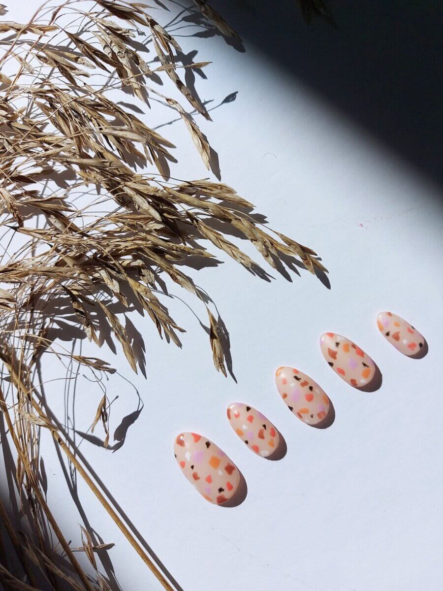 Five press-on multi-coloured nails paying on a white background  