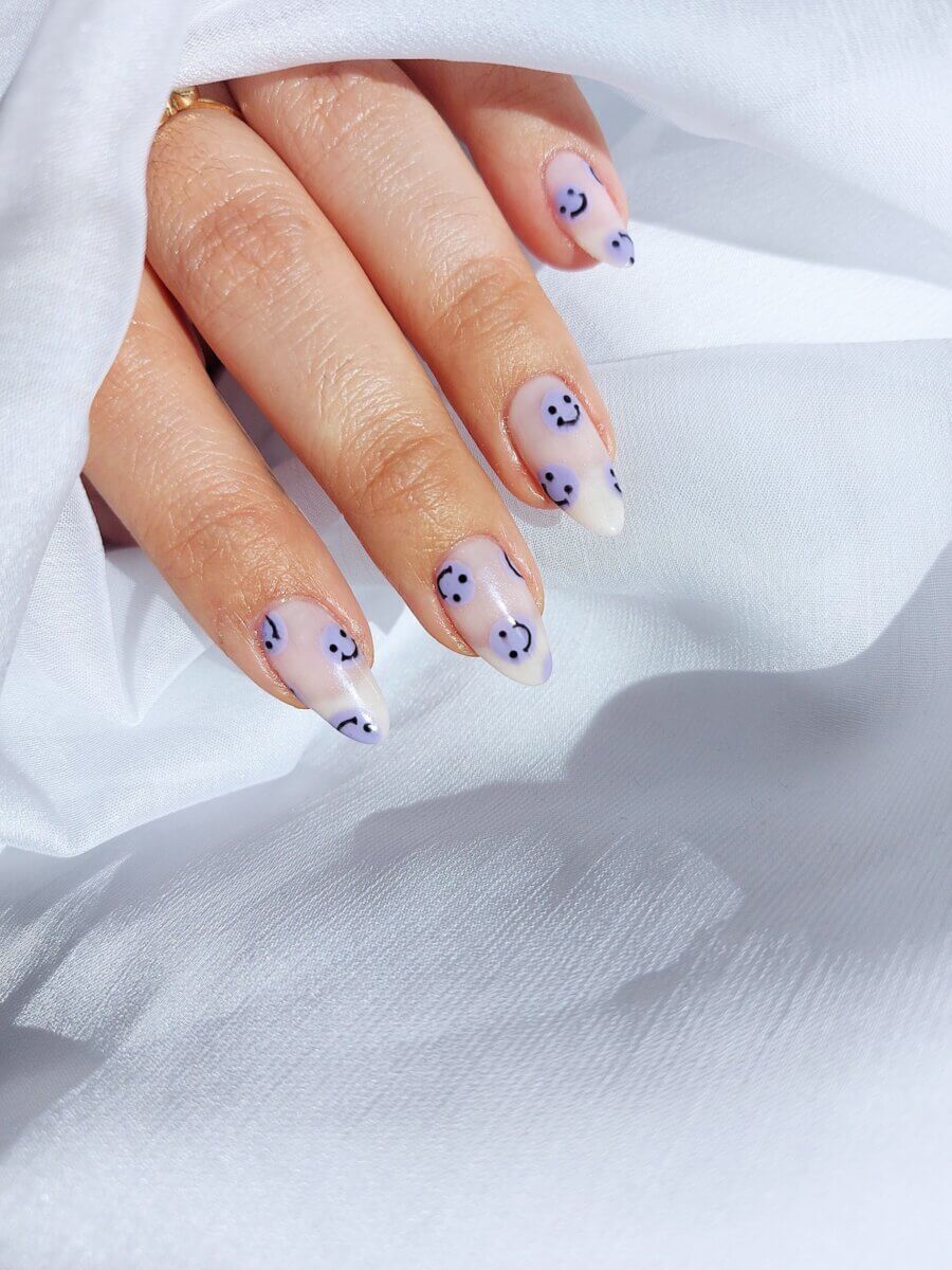 4 white, blue and black press-on nails on a woman's left hand