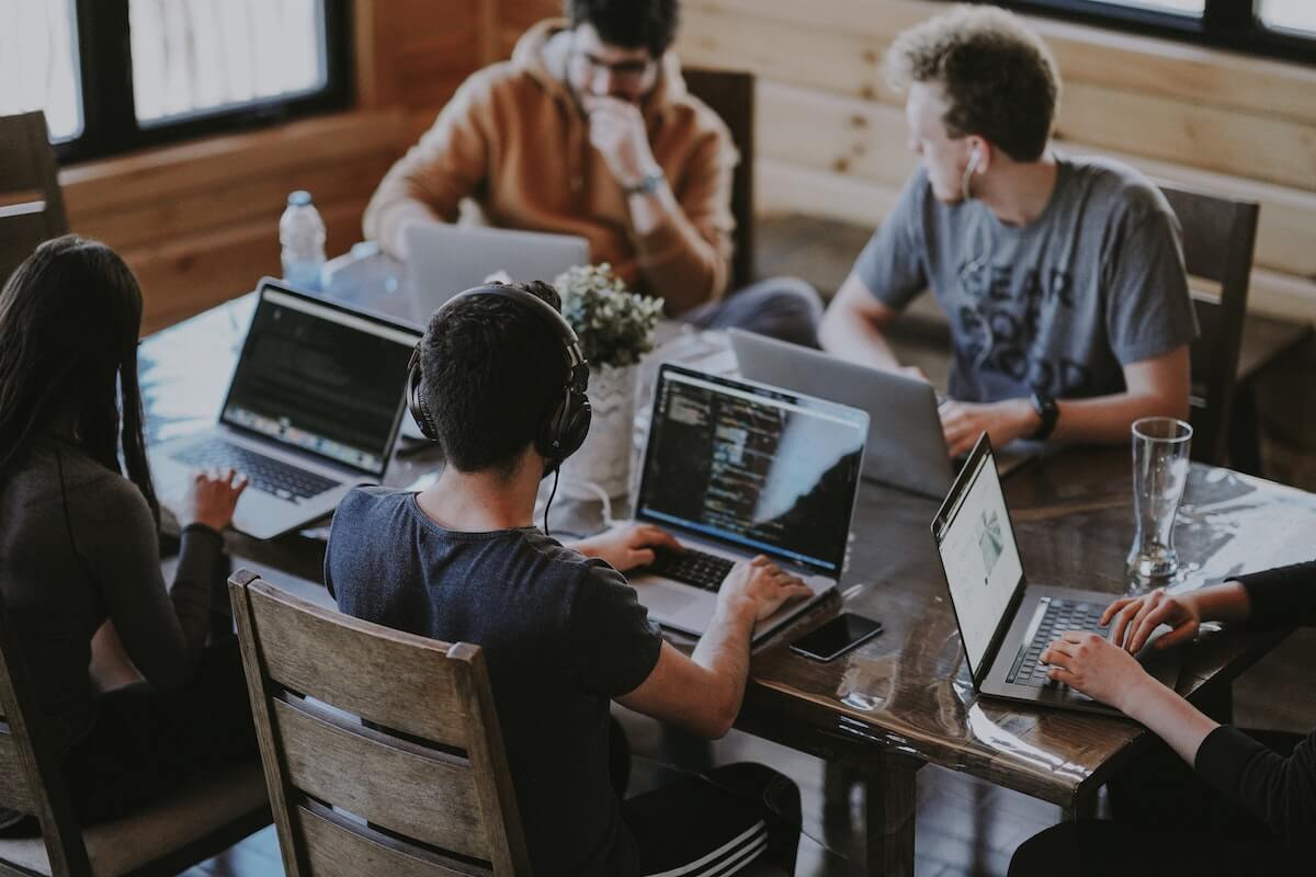 Four businesspeople working at laptops at a table, an example of more Toronto startups creating a sustainable world