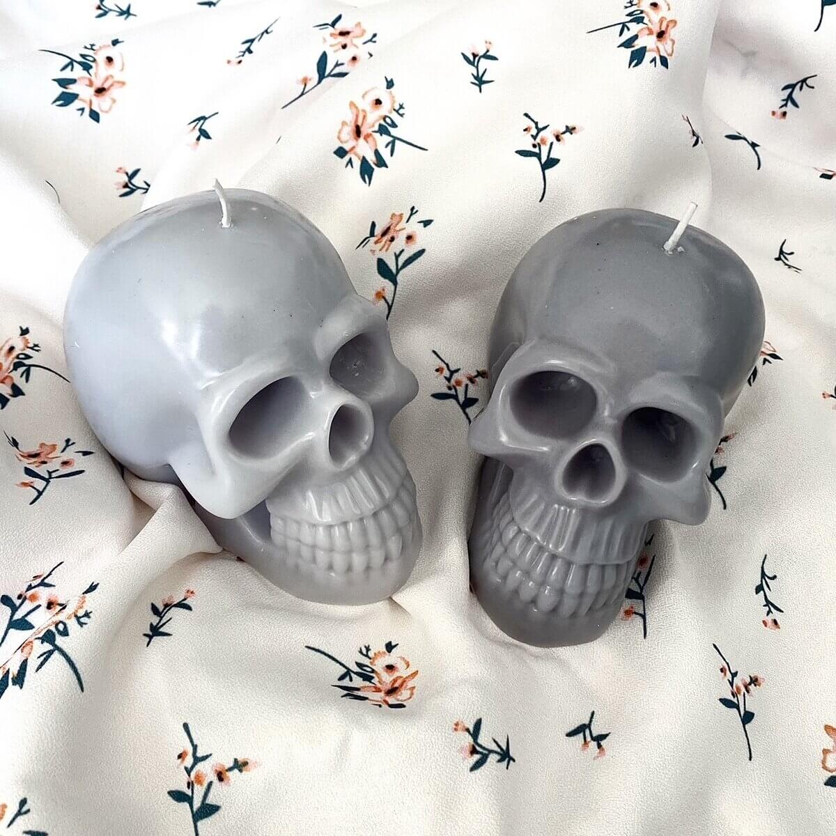 2 grey wax skulls on a white sheet