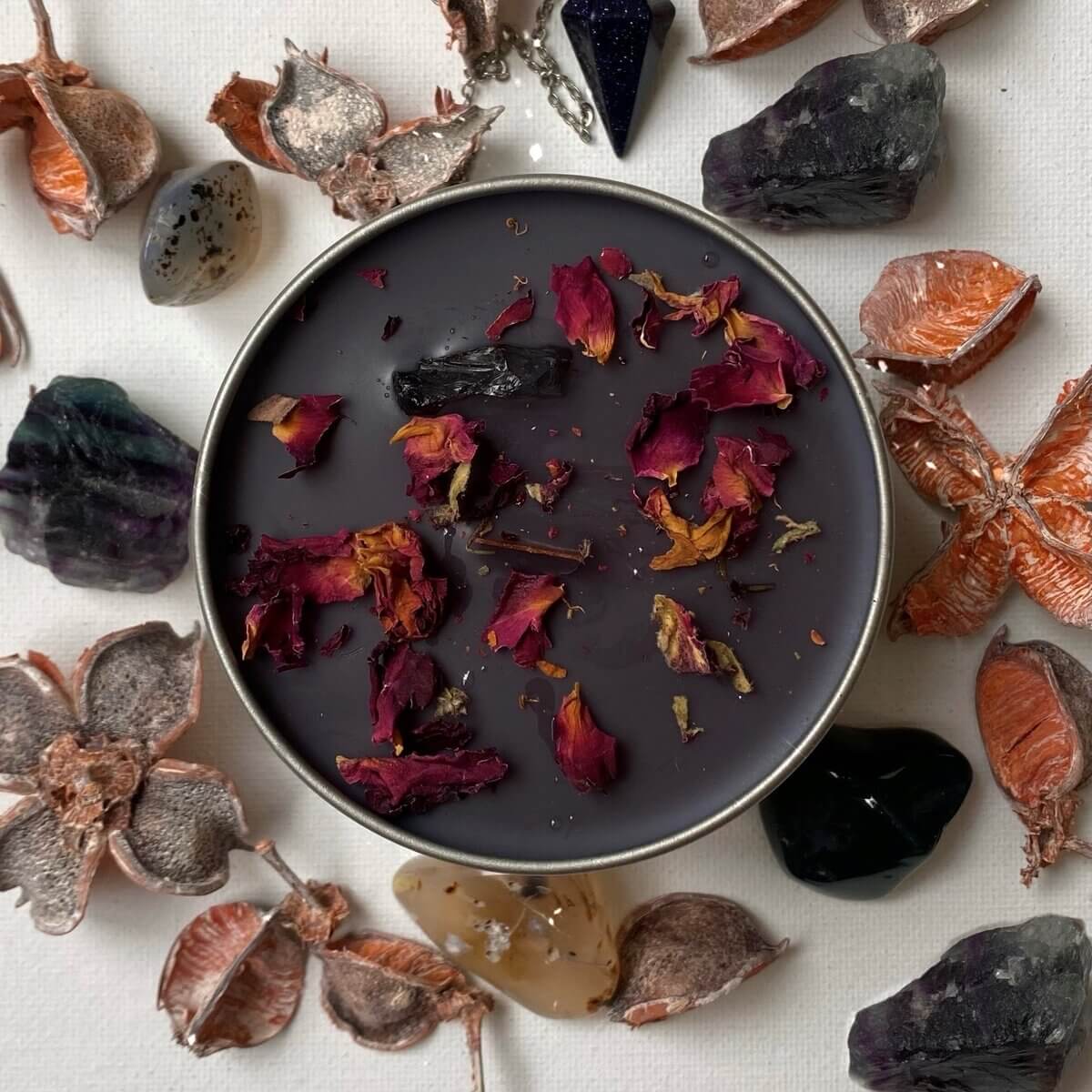 a dark circular candle with red & orange leaves, surrounded by ornaments