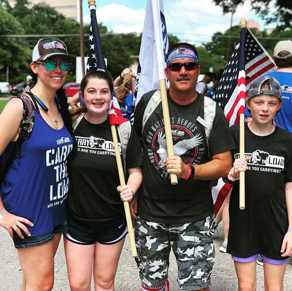 4 people carrying flags at a carry the load march in dallas texas