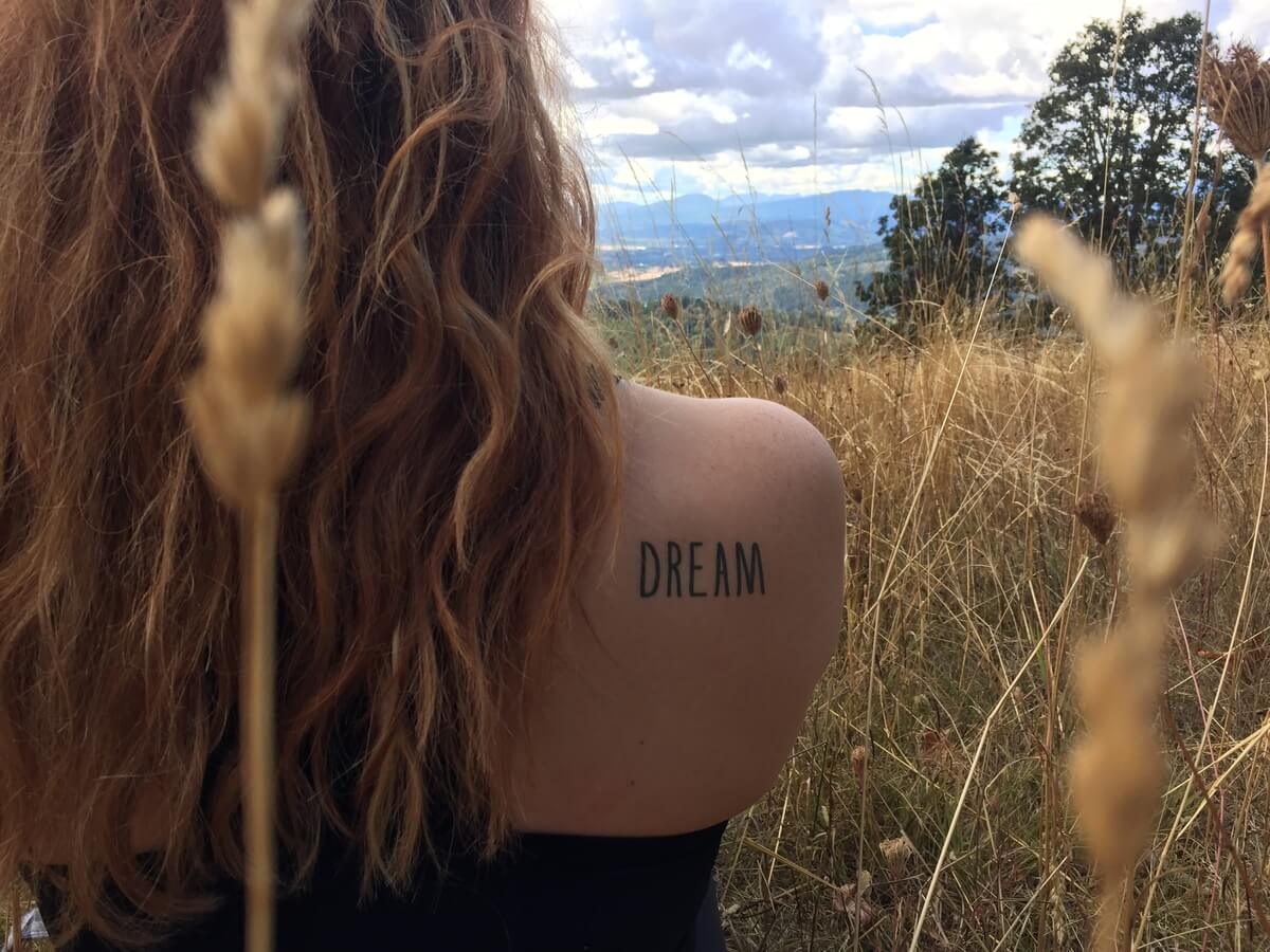 A conscious ink temporary tattoo on a woman's shoulder that says Dream 