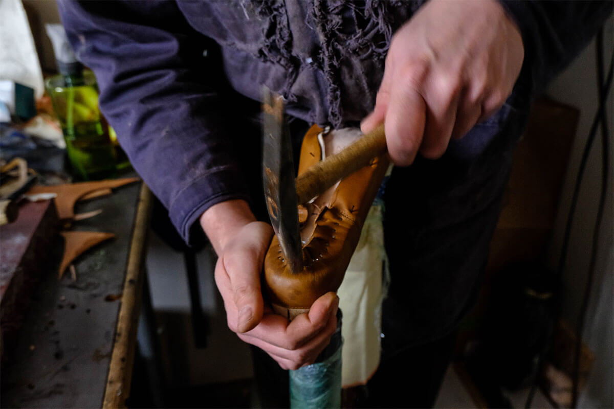 Adam Finn hammering a nail to help shape the heel of the mule on this pair of custom made shoes