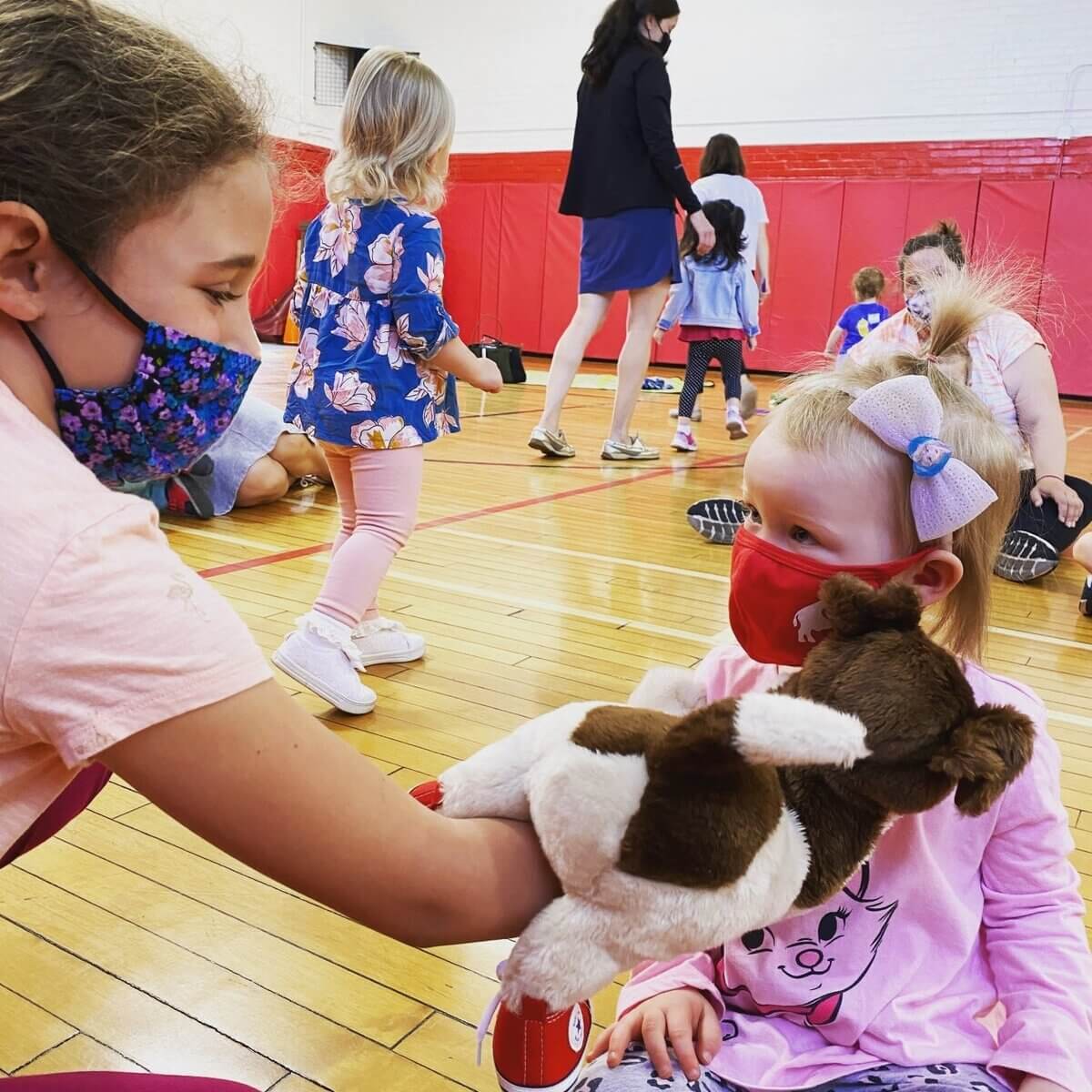 2 young girls playing with a plush dog