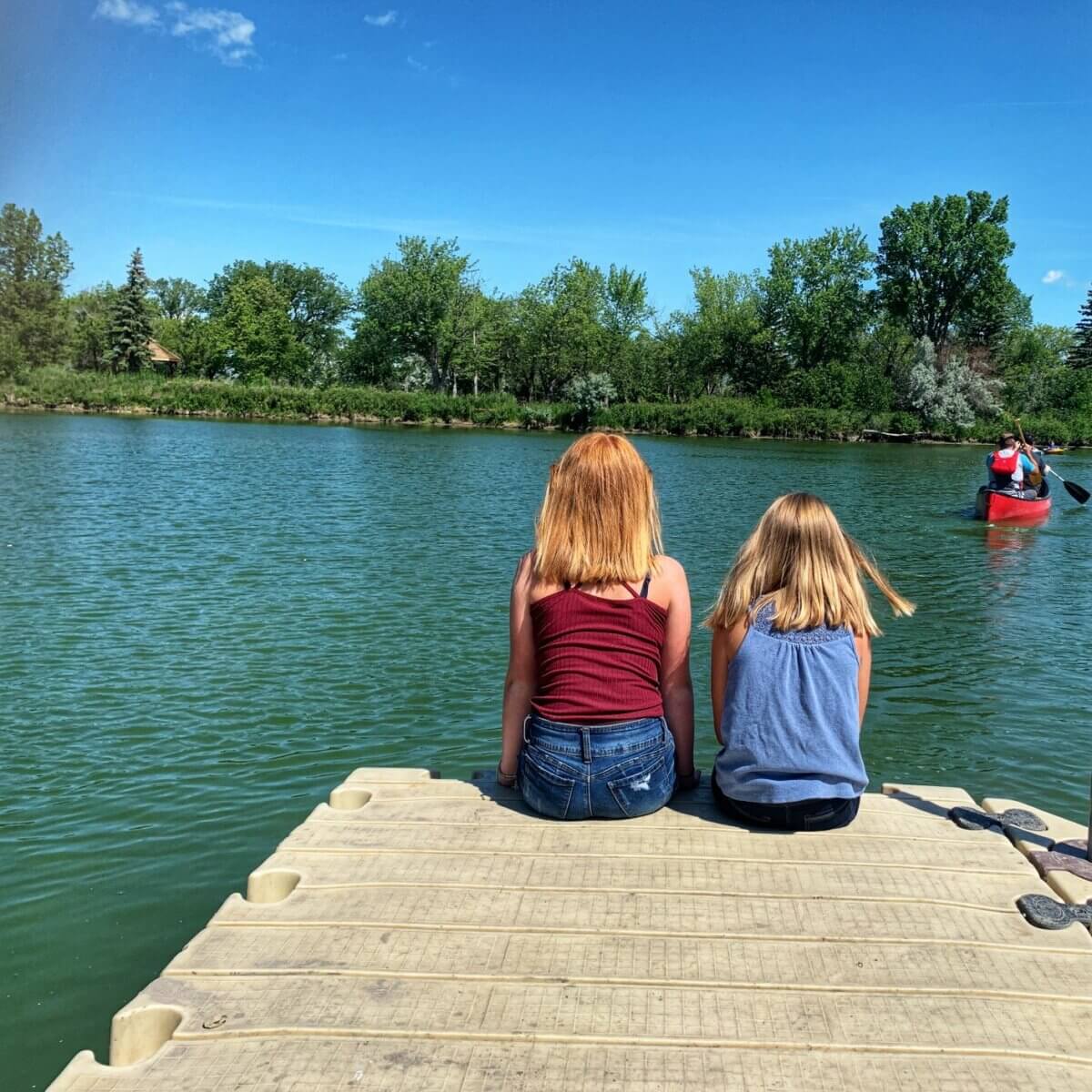 2 girls sitting on a dock 