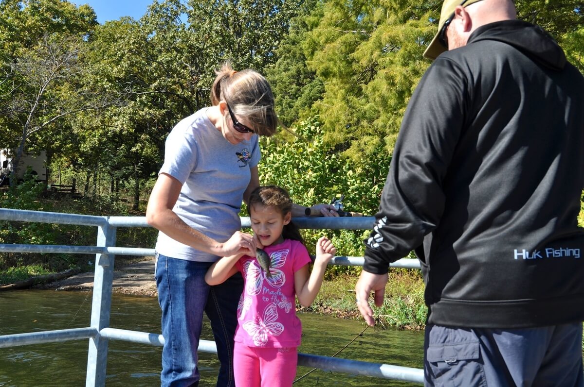 young girl holding a fish with woman and man