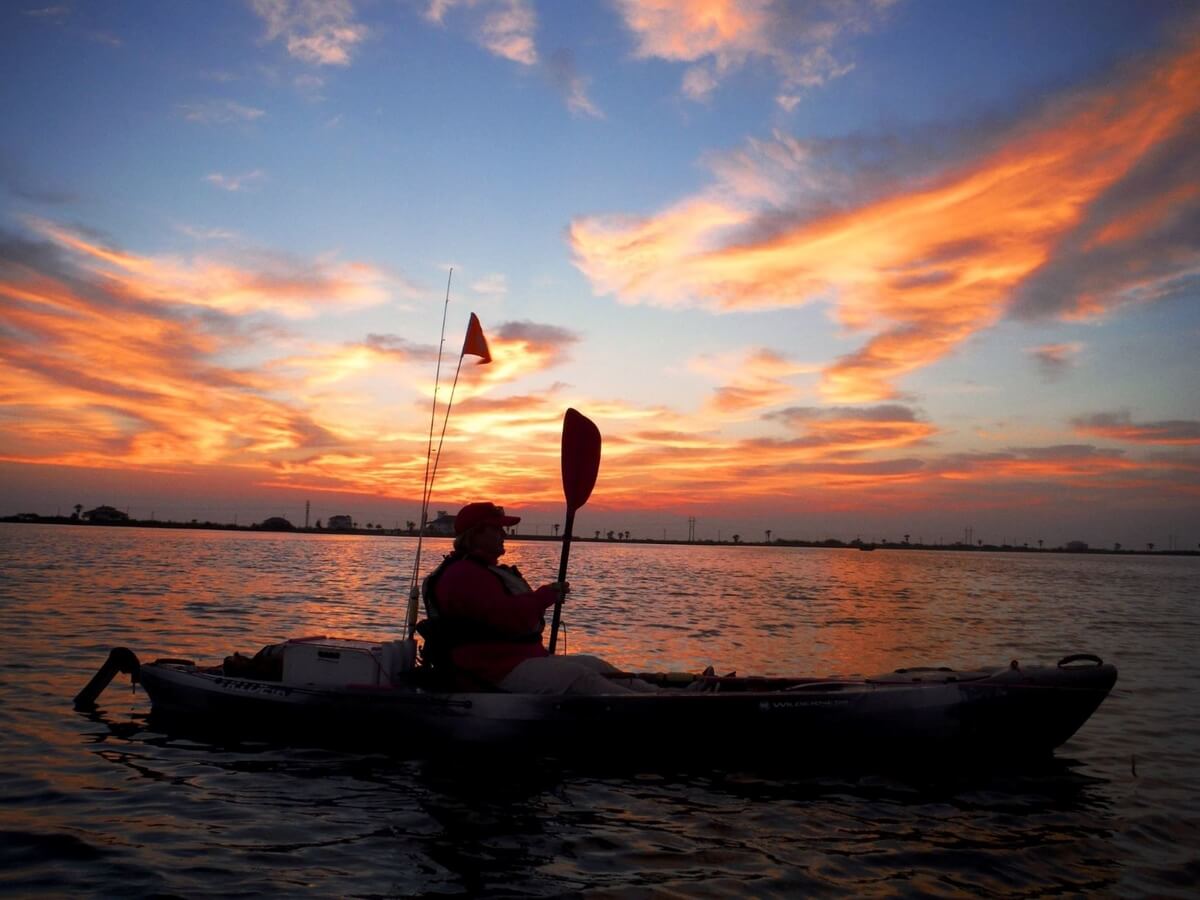 kayak fisherman at sunset on a lake