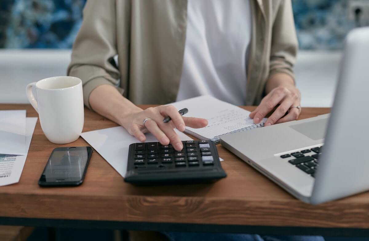 A woman running a calculator at a table to help address financial debt