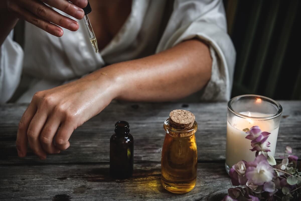 A woman putting essentials oils on her arm, one of 4 ways to get a better sleep