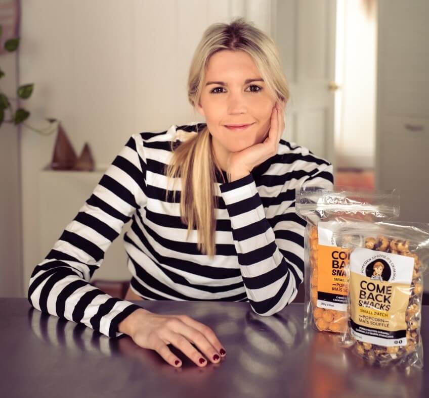 emily o'brien at a table with 2 bags of comeback snacks, popcorn with a mission