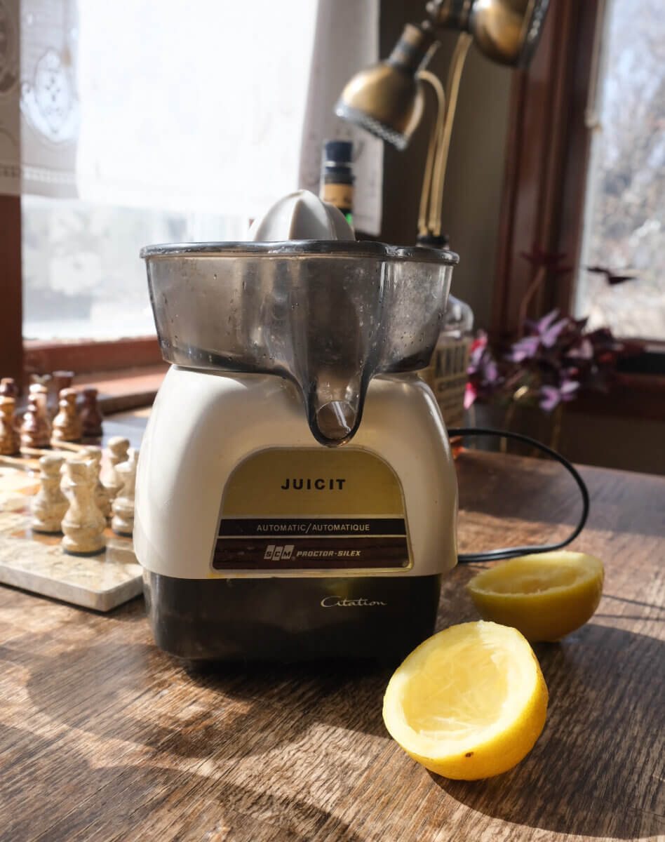 vintage juicer on a kitchen counter beside lemon halves