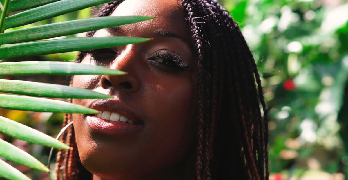 headshot of stacey martin behind a palm leaf in nevis