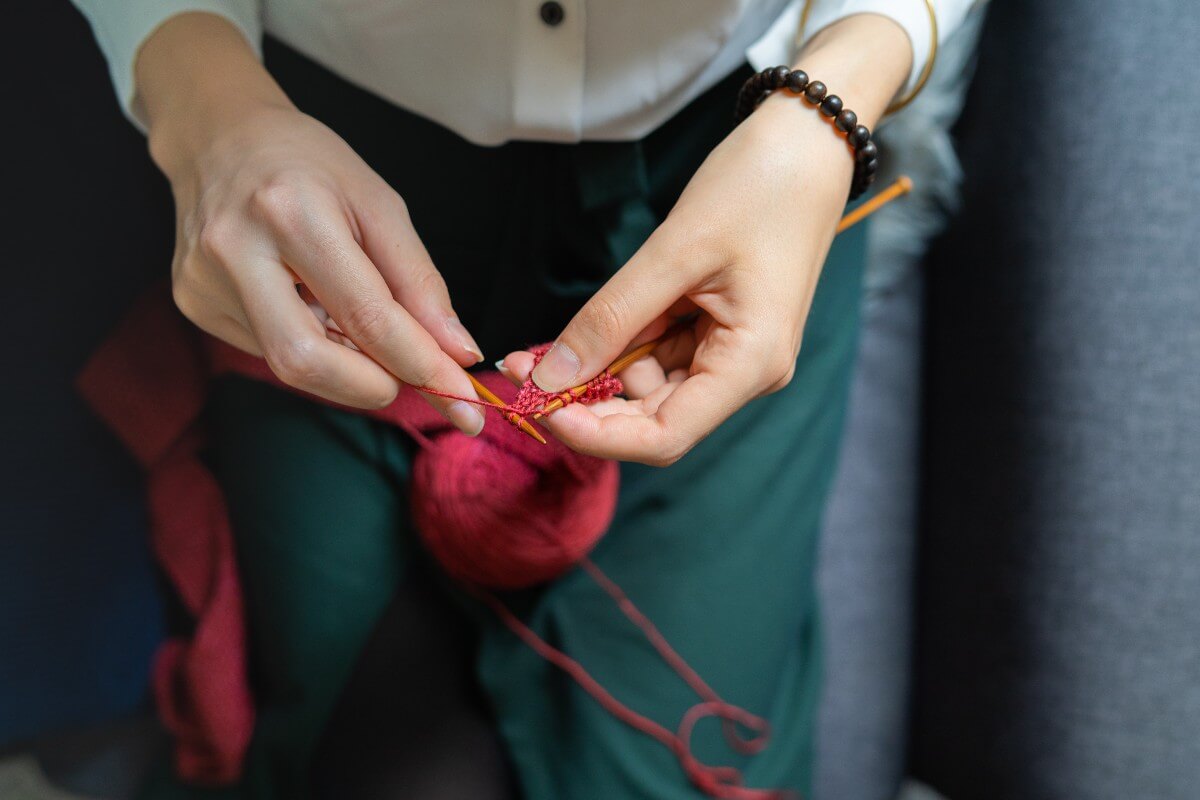 a woman knitting with red yarn