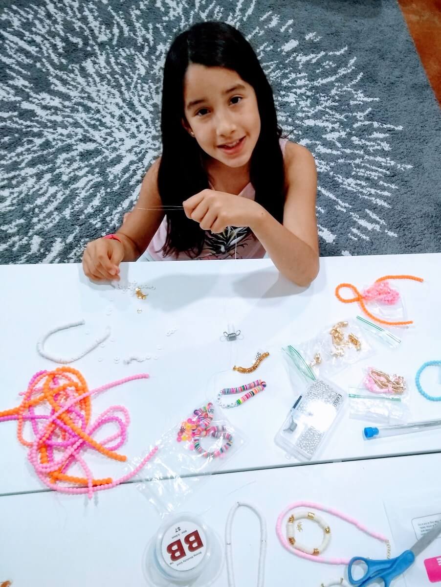 young girl making bracelets for shining brownies to help other kids