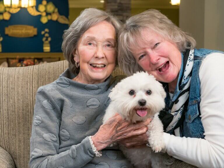 2 women with small white dog as part of doggies for dementia