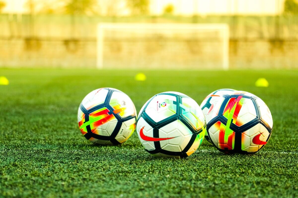 4 soccer balls on a pitch used for for grassroots soccer 