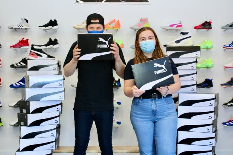 2 young people at John Howard Society beside donation of PUMA shoes