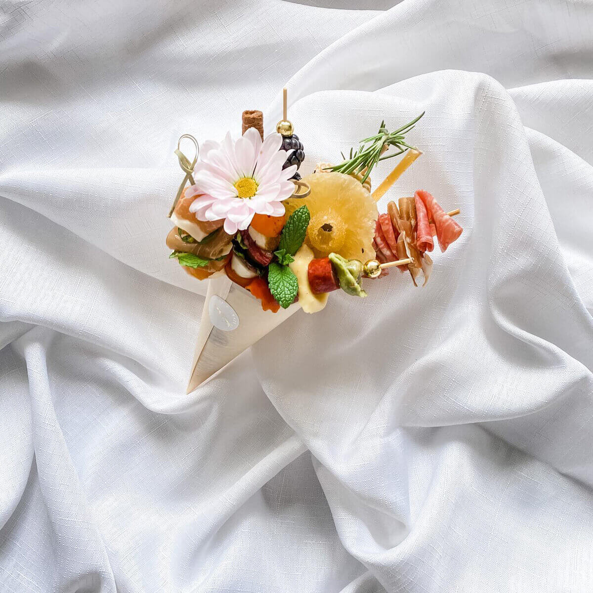 a colourful appetizer cone with flowers on a white sheet