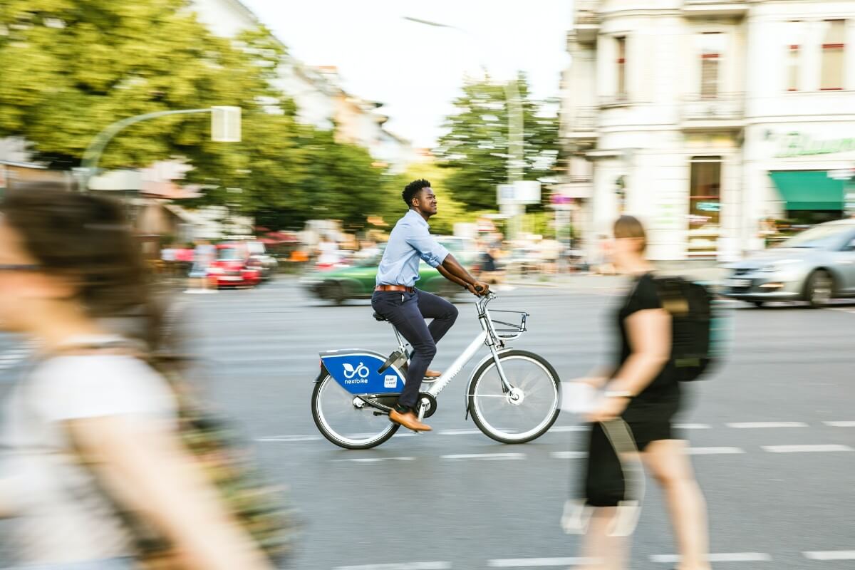 man riding a bike in a city to reduce carbon and help save the oceans