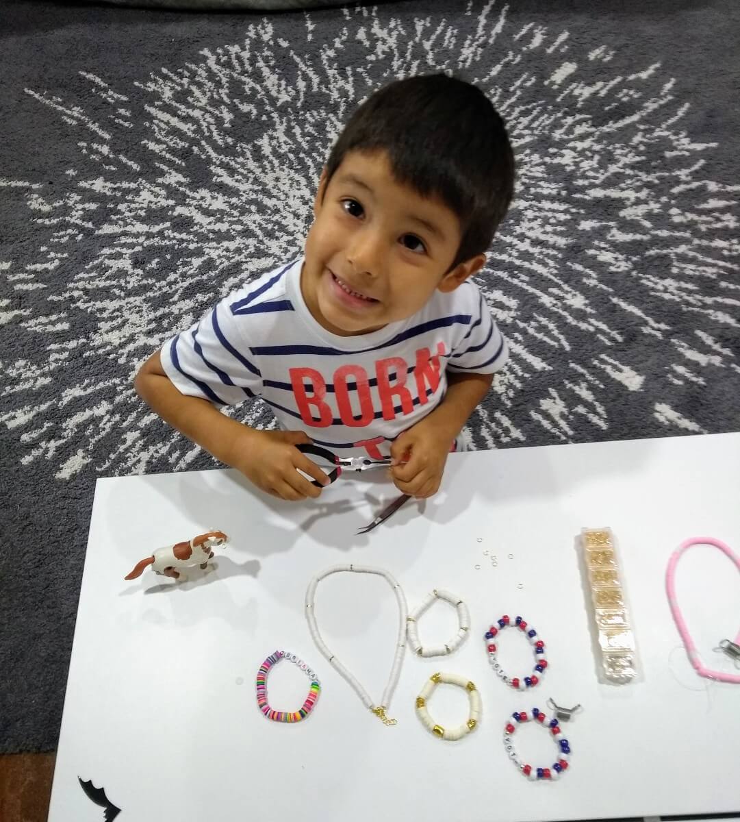 young boy making bracelets for shining brownies to help other kids