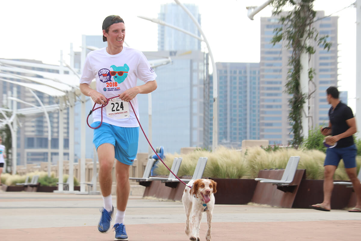 man running a dog in summer in the city