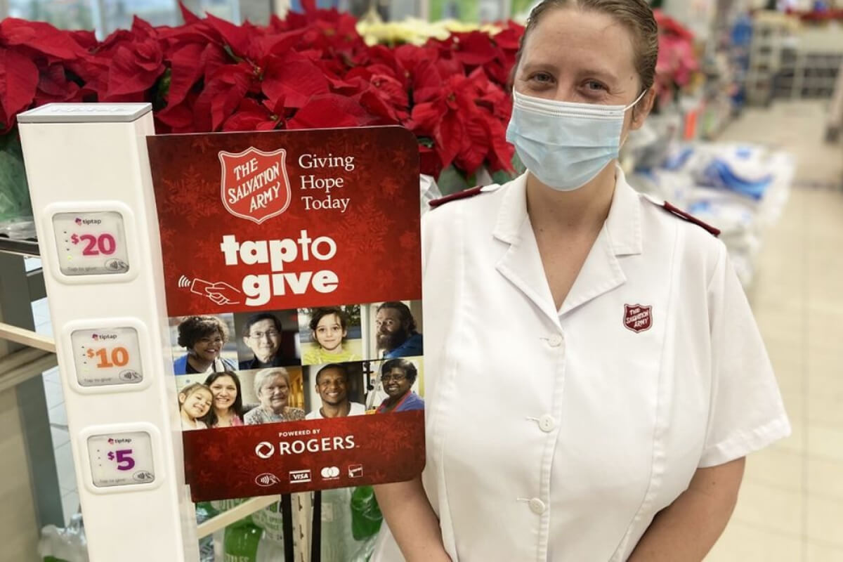 Salvation Army volunteer in front of a kiosk using tiptap technology