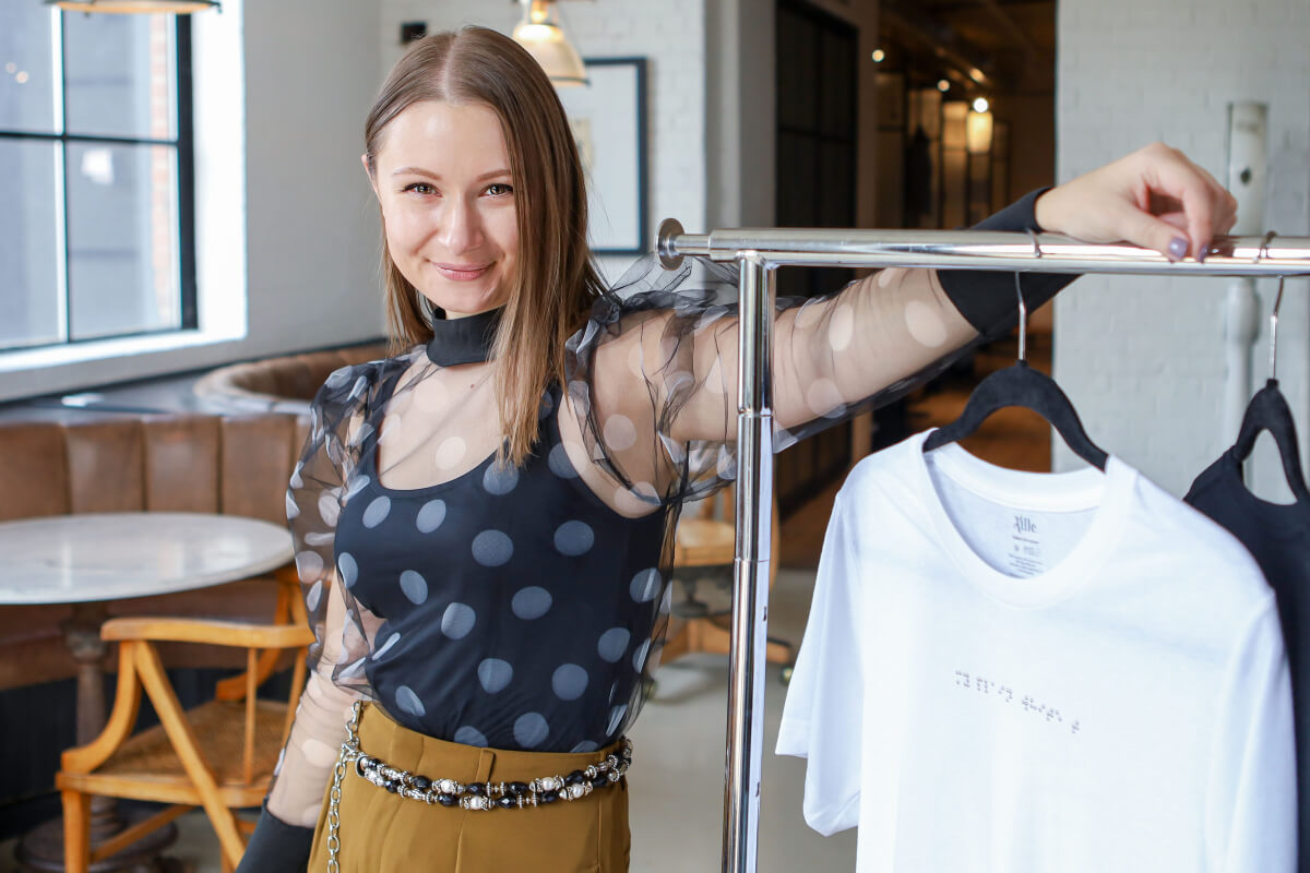 founder of allie design in navy and gold beside a rack of her inclusive fashion