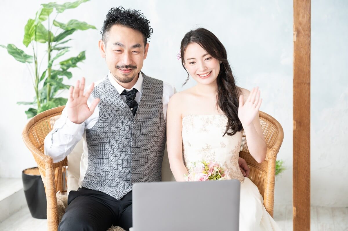 wedding couple waving at a laptop using Zoom 