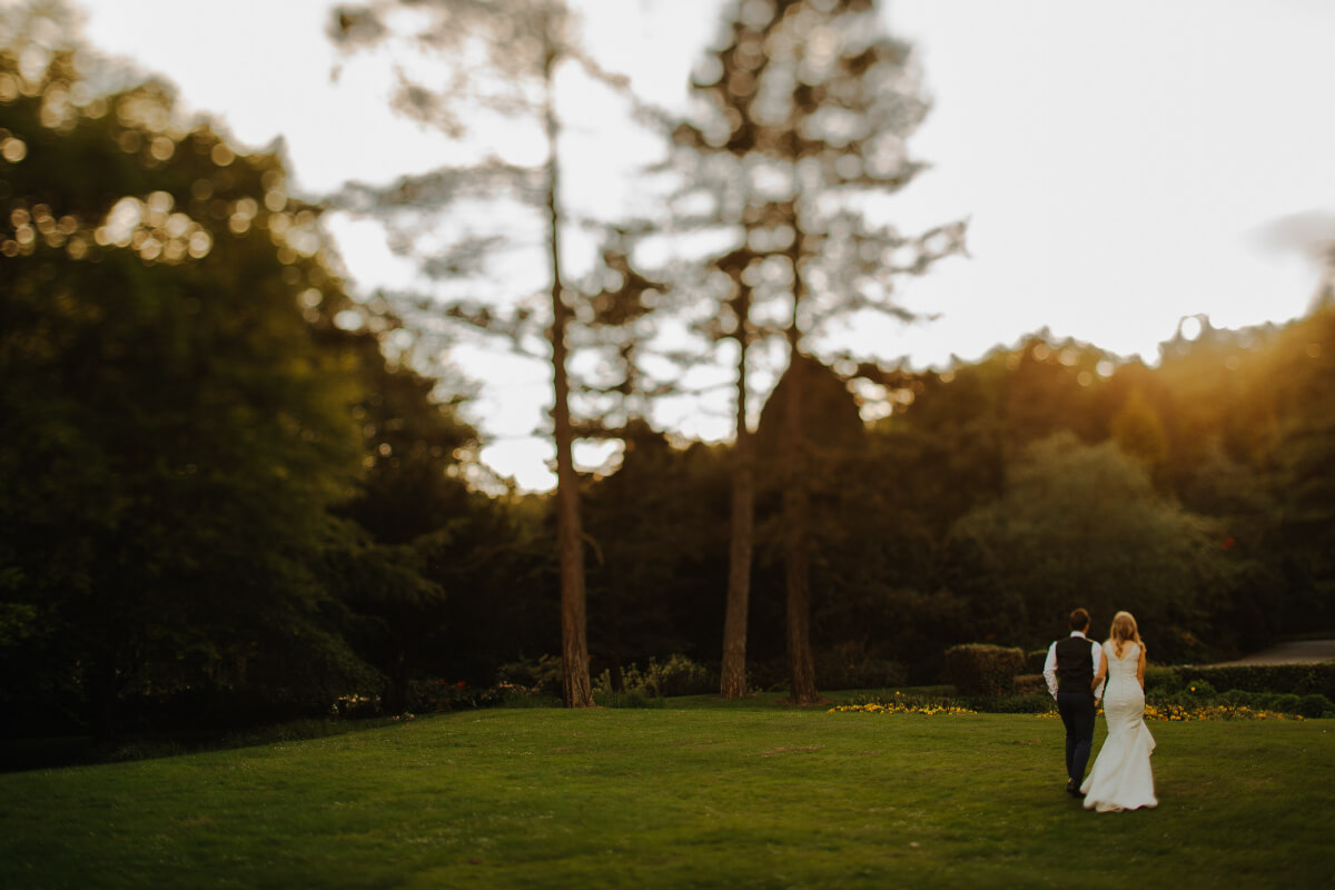 a man and woman walking at their outdoor wedding