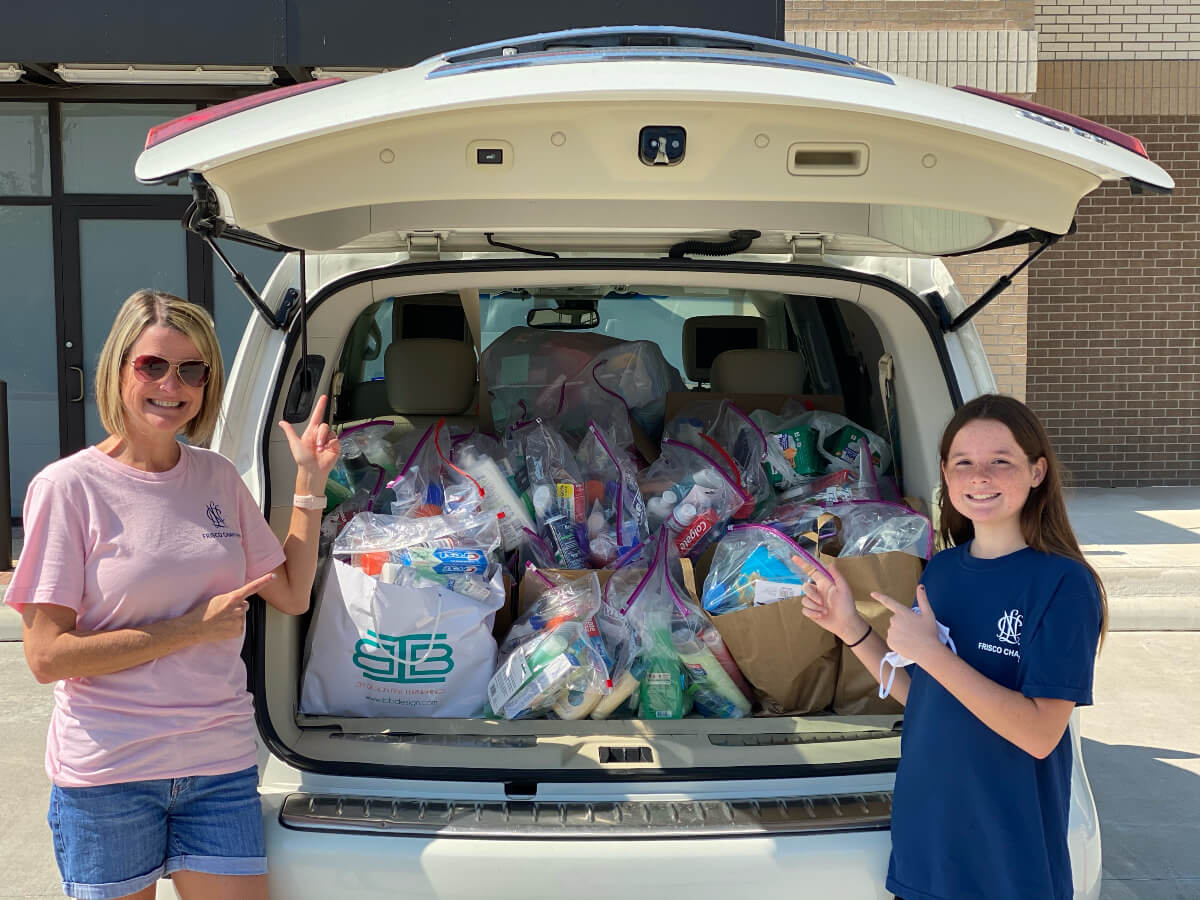 woman and young girl beside a vehicle full of hygiene products donated by Refresh Frisco