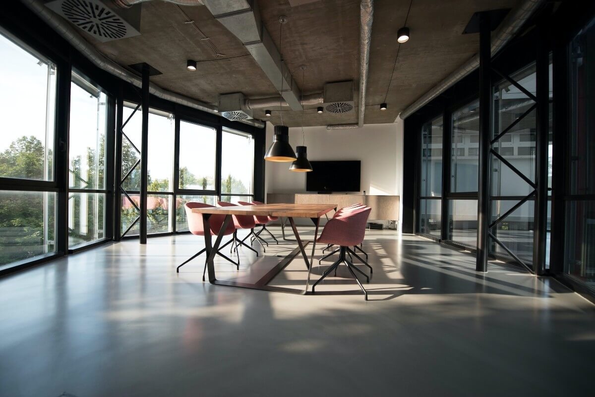 meeting table and chairs in large meeting space with many windows