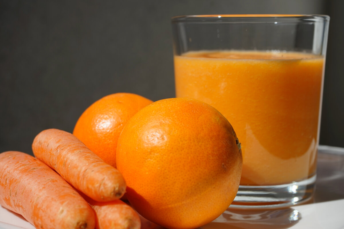 glass of juice, oranges, carrots for juicer recipes