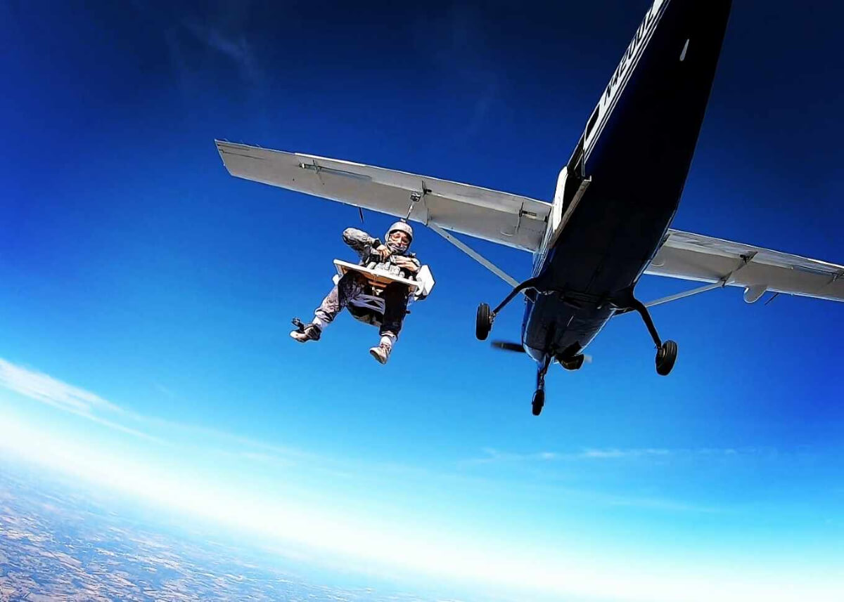 woman supsended from plane before skydiving & painting 