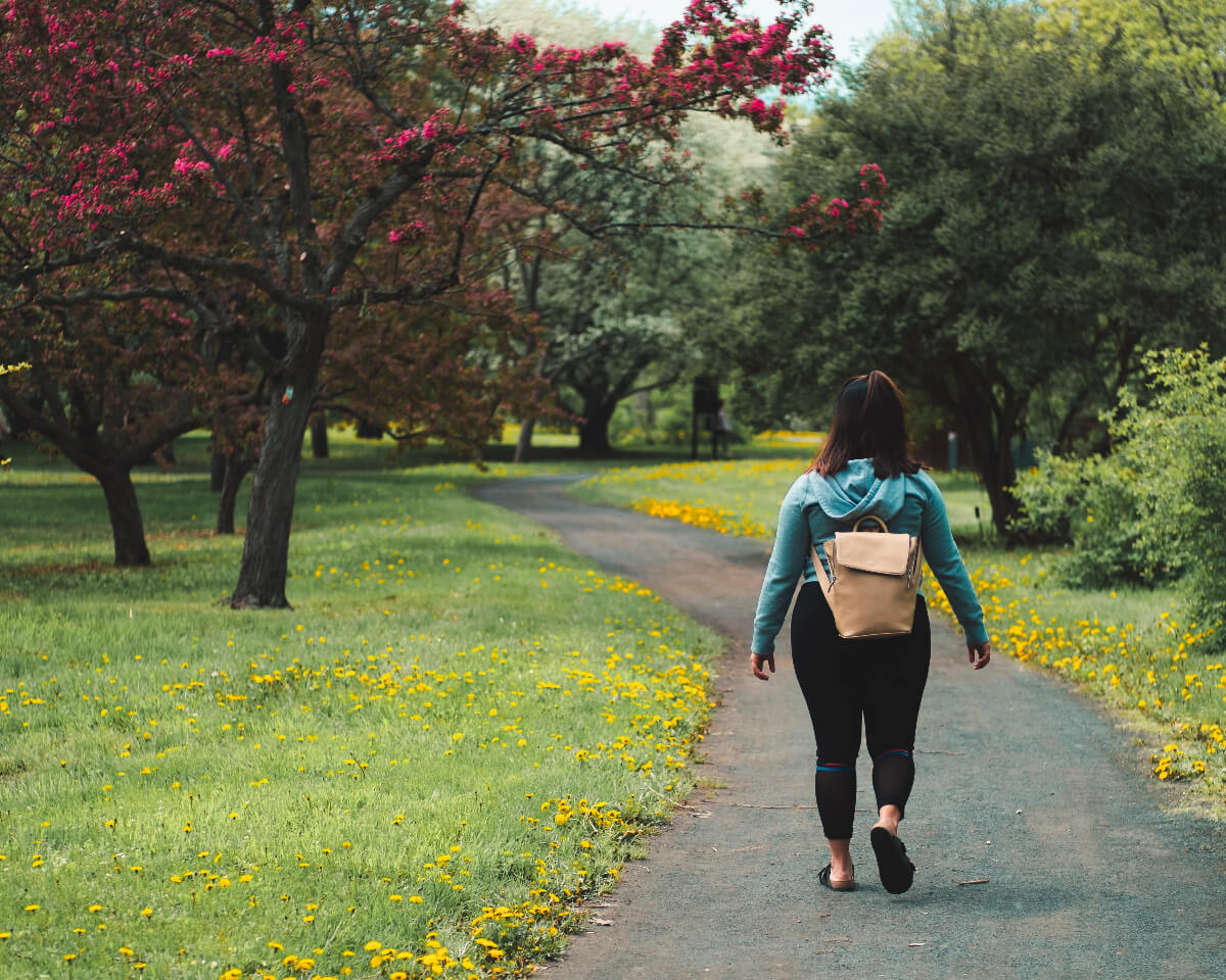 a woman walking in a park, enjoying meditation benefits