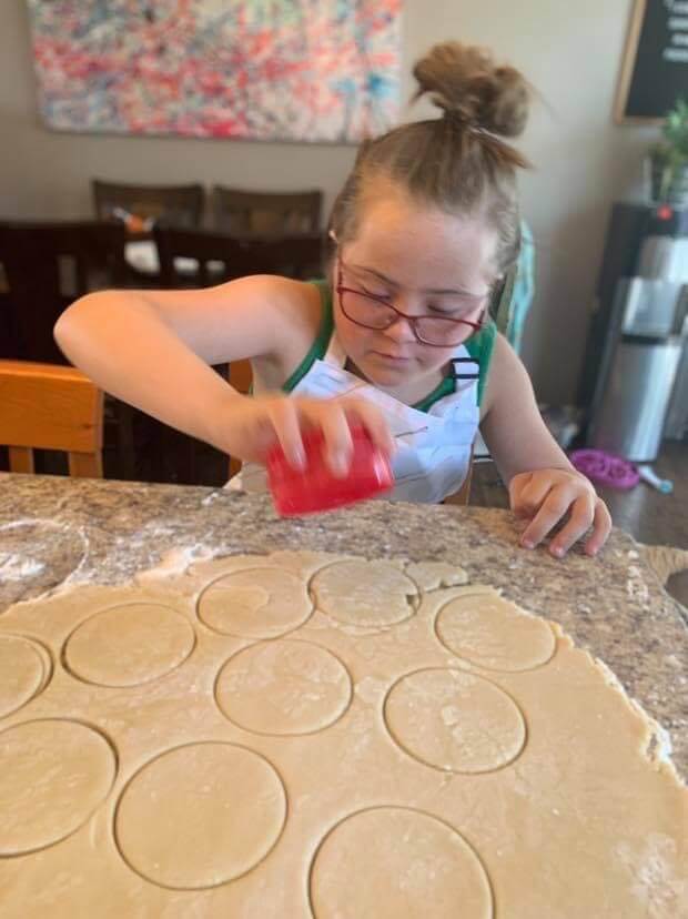 young girl cutting cookies in rolled dough for 21treats