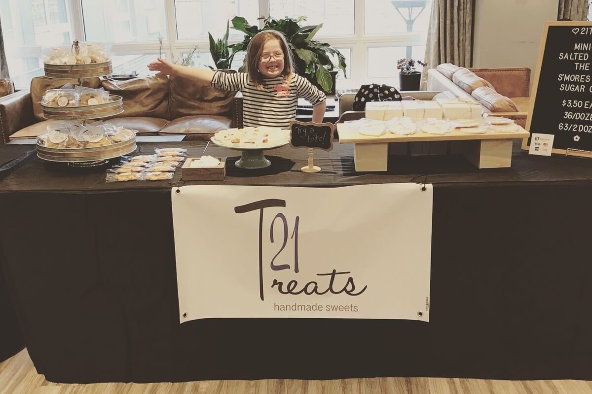 girl standing behind a 21Treats table of cookies